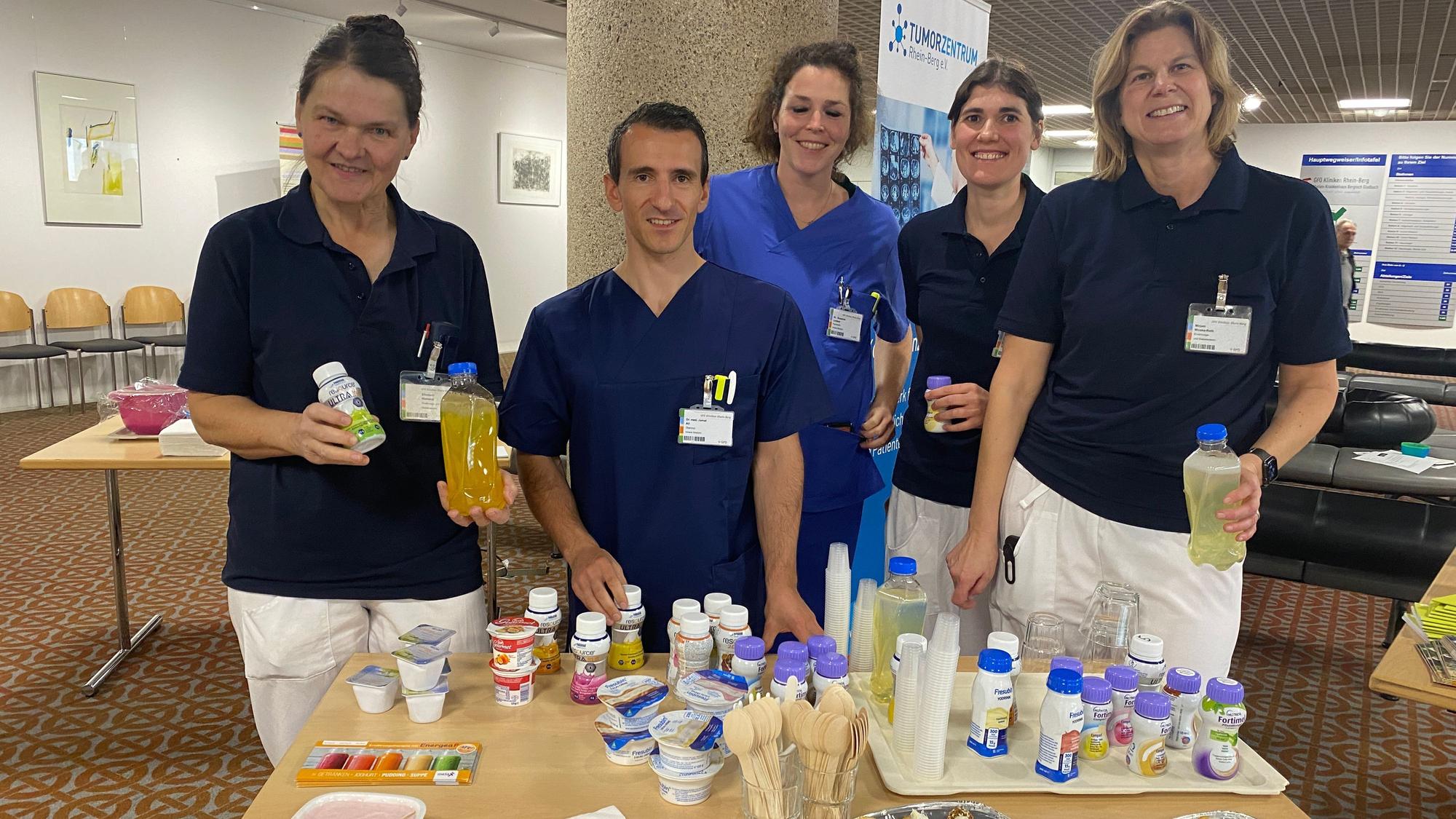 Ein Team des Marienkrankenhauses steht an einem Tisch mit Lebensmittel, die auch kranke Menschen gut essen können.