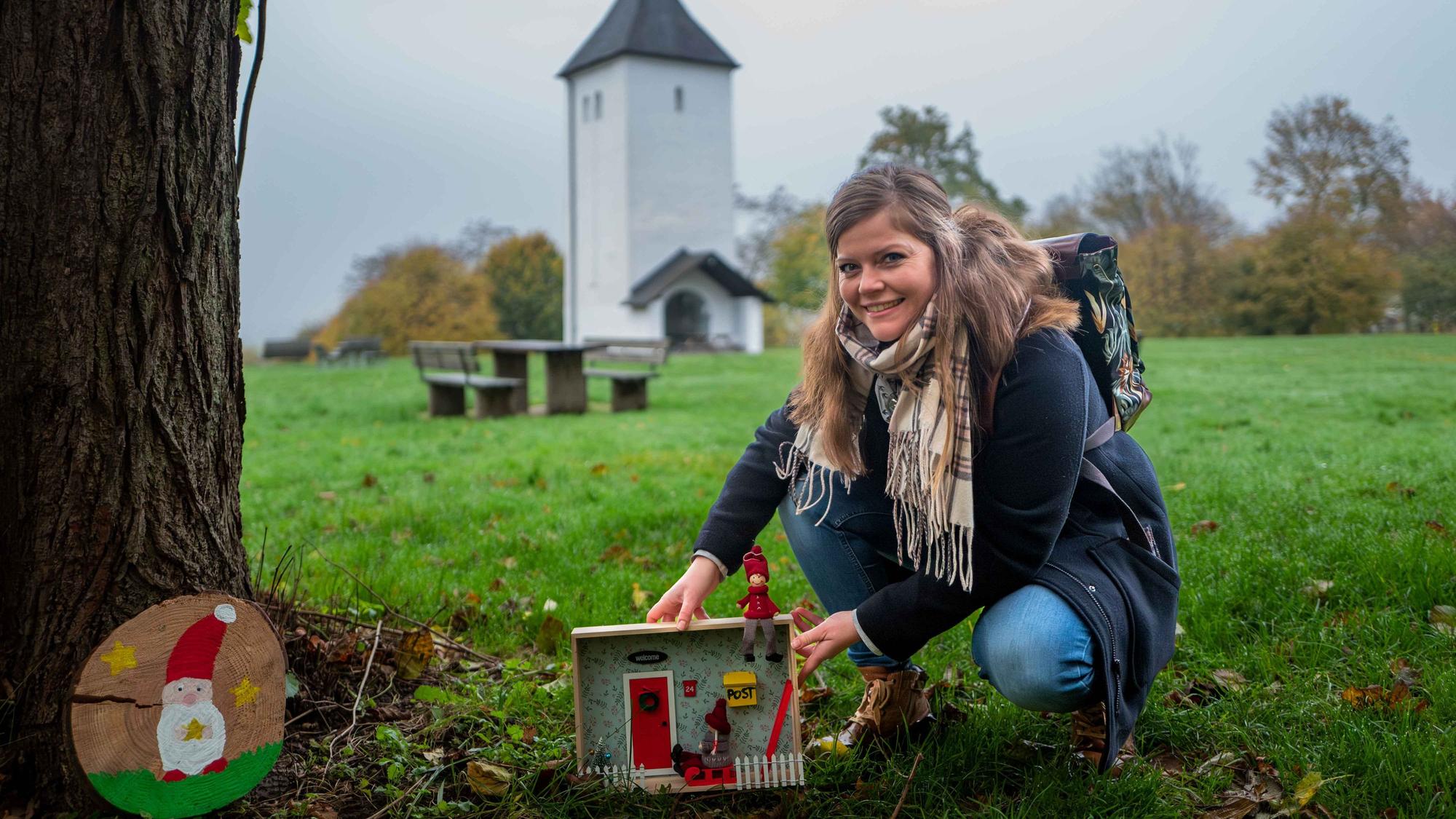 Das Bild zeigt Patricia Dreesbach vor dem Swister Turm, wie sie an einem Baum eine Wichtelwohnung aufstellt.