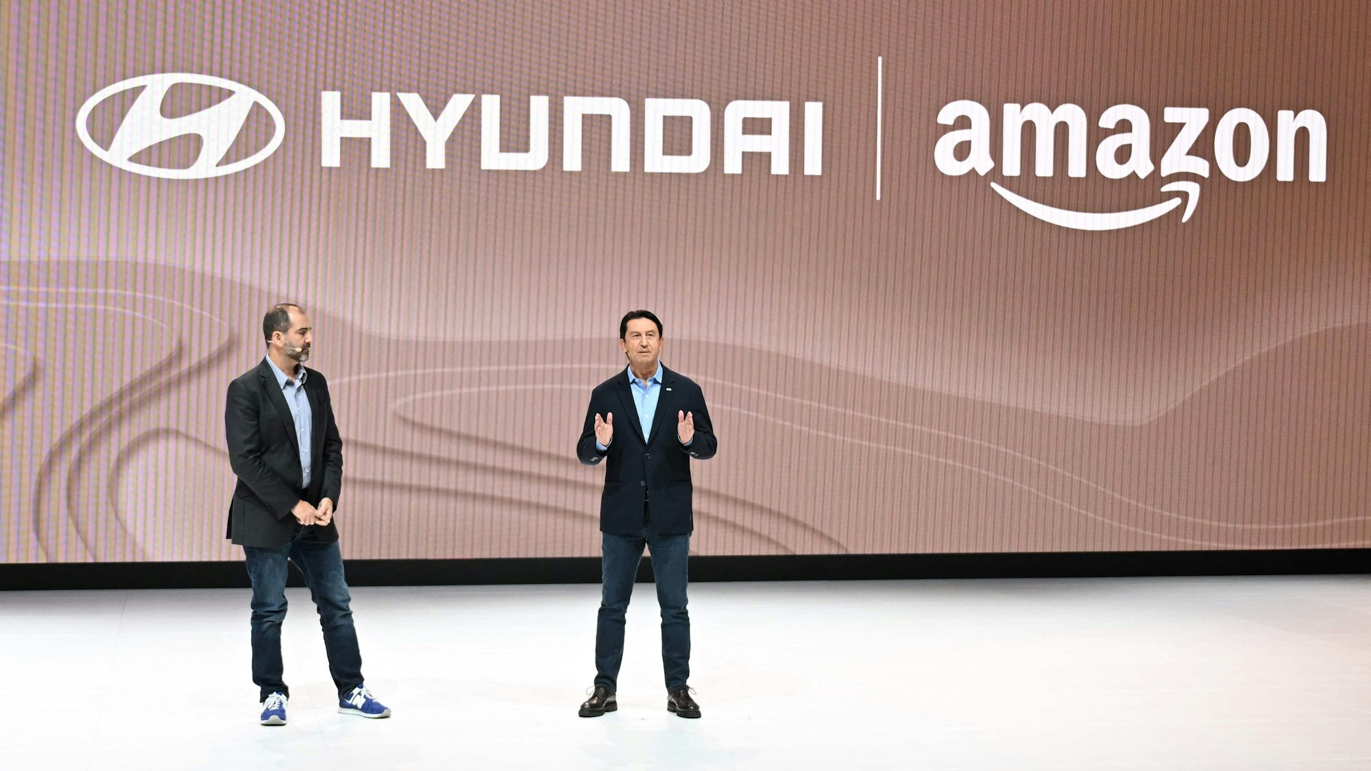Marty Mallick (Amazon) und Jose Munoz (Hyundai) stehen auf einer Bühne vor den digital angeworfenen Logos ihrer Firmen.