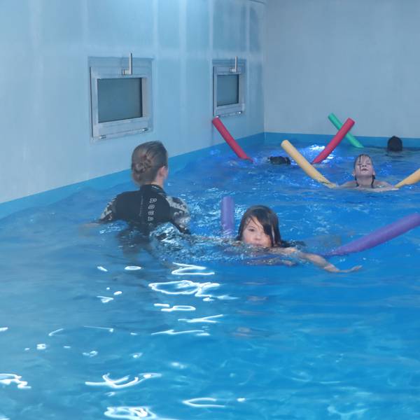 Auf dem Foto sind Kinder zu sehen, die im Schwimmcontainer unterrichtet werden.