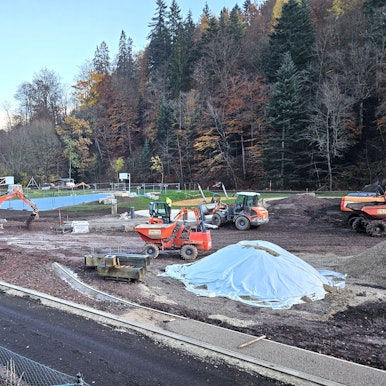 Blick auf die Baustelle mit mehreren Baggern und Arbeitern.
