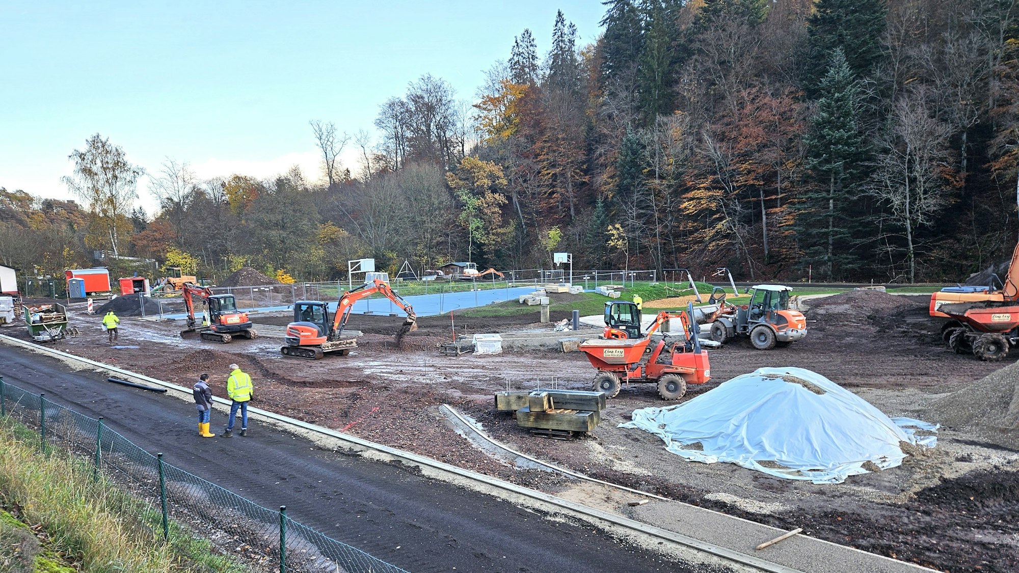 Blick auf die Baustelle mit mehreren Baggern und Arbeitern.