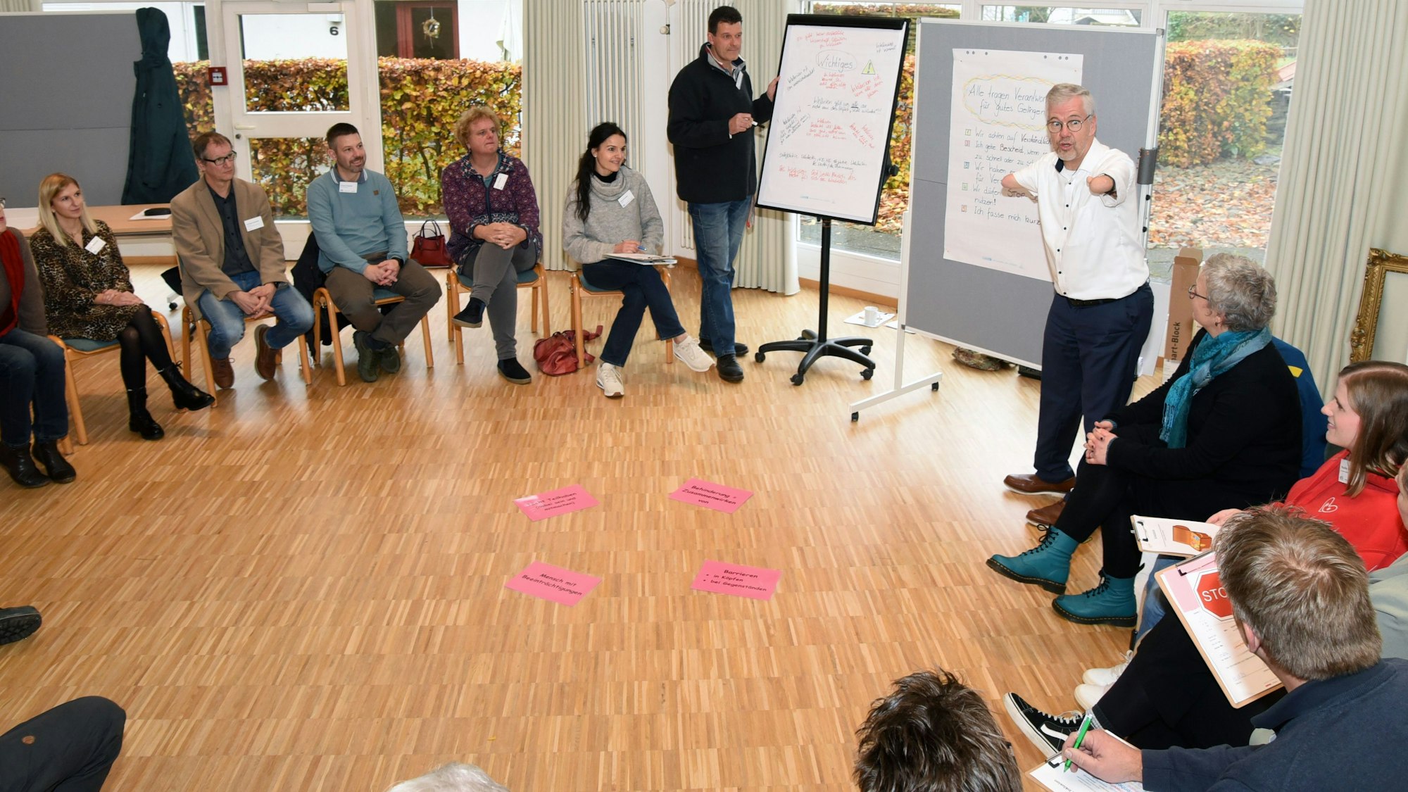 Unter der Moderation von Rainer Schmidt (rechts) ging es beim Auftaktworkshop in Wiehl-Oberbantenberg zunächst um das Verständnis von „Inklusion“. Hier steht der Moderator an einem Flipchart, die Teilnehmenden sitzen in einem Kreis um ihn herum.