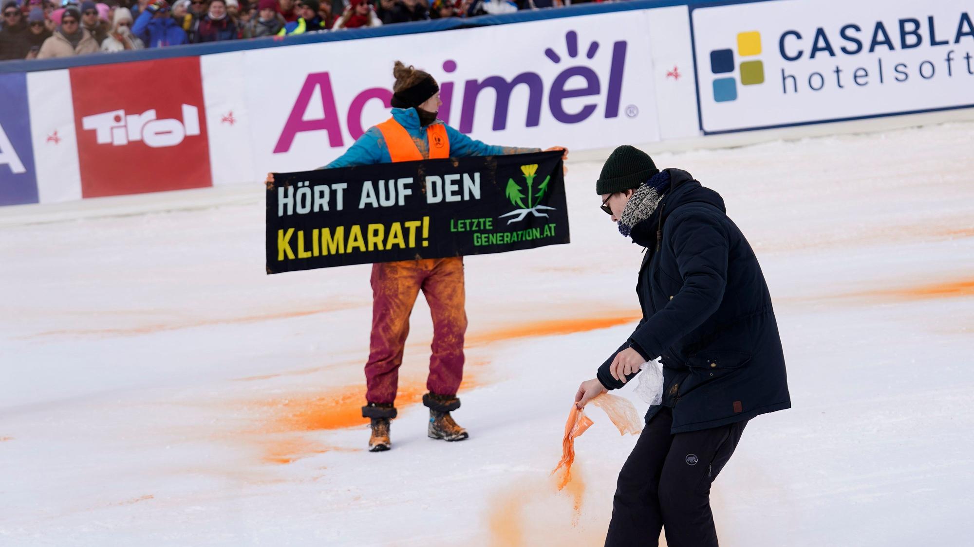 Ein Demonstrant der Letzten Generation versprüht Farbe im Zielbereich eines alpinen Skiweltcup-Slaloms der Herren in Gurgl.