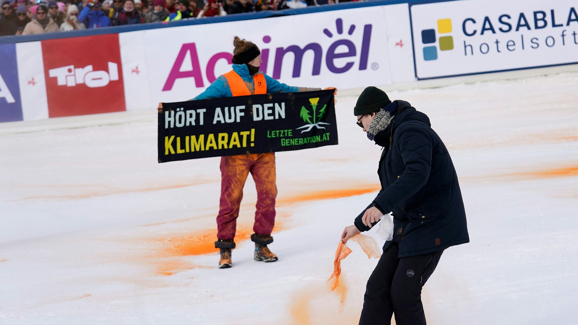 Ein Demonstrant der Letzten Generation versprüht Farbe im Zielbereich eines alpinen Skiweltcup-Slaloms der Herren in Gurgl.