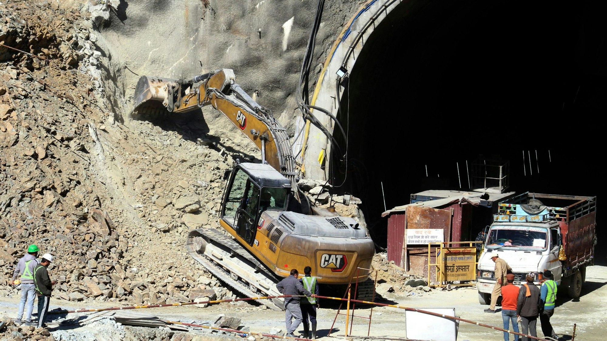 18.11.2023, Indien, Uttarakhand: Ein Bagger arbeitet am Eingang eines im Bau befindlichen Straßentunnels, der eingestürzt ist. Die Bohrarbeiten zur Rettung von etwa 40 Arbeitern in einem eingestürzten Autobahntunnel im Norden Indiens sind vorübergehend unterbrochen worden. Ein eigens aus der Hauptstadt Neu Delhi eingeflogenes Bohrgerät habe am Freitagnachmittag (17.11.2023) seine Arbeit eingestellt, nachdem ein lautes Knacken im Tunnel zu hören gewesen sei, berichtete die Nachrichtenagentur PTI am Samstag unter Verweis auf Behörden. Das Geräusch habe Panik bei den Rettungskräften ausgelöst. Foto: ---/AP/dpa +++ dpa-Bildfunk +++