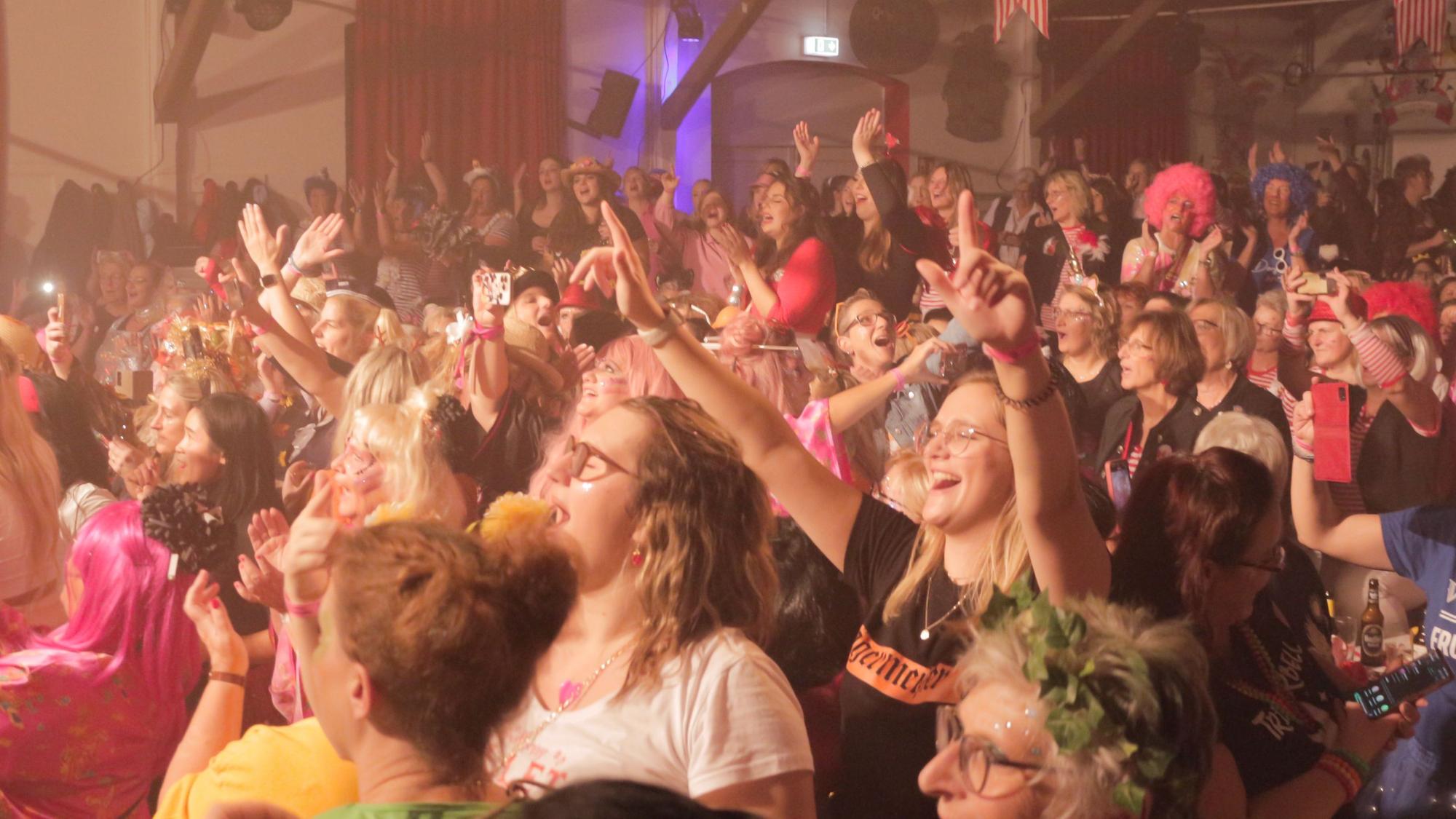 Bunt kostümierte Frauen feiern im voll besetzten Iversheimer Dorfsaal ausgelassen Karneval.