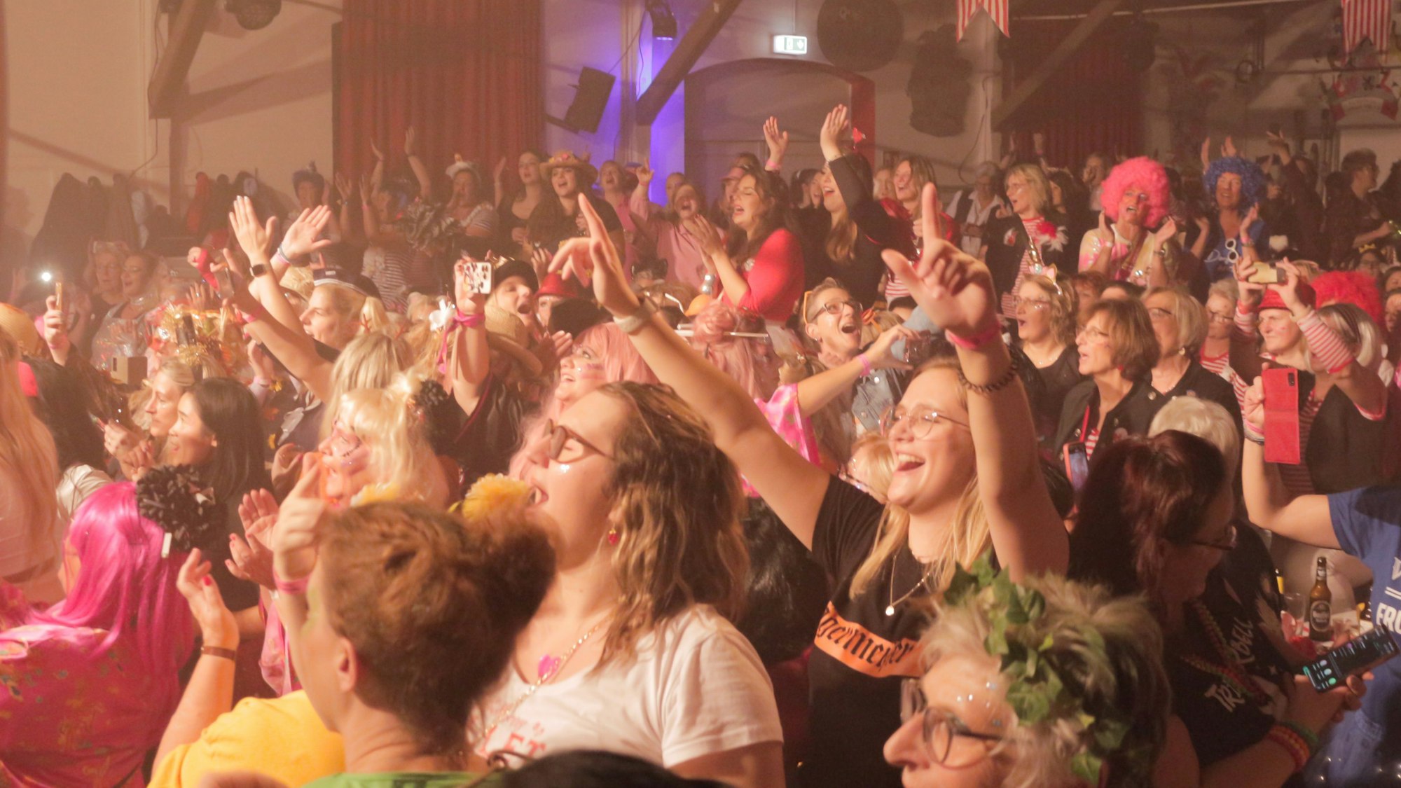 Bunt kostümierte Frauen feiern im voll besetzten Iversheimer Dorfsaal ausgelassen Karneval.