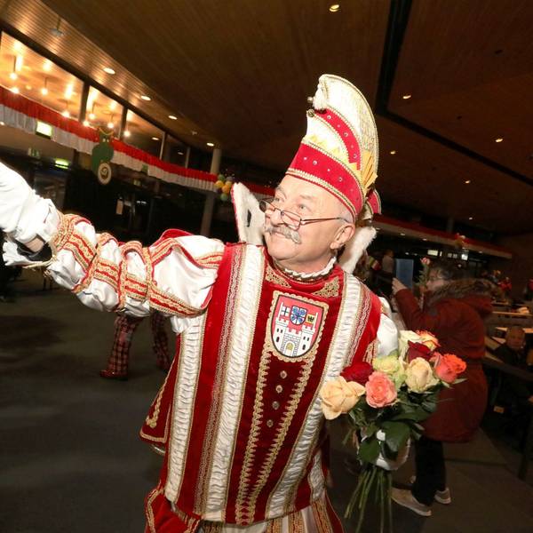 Eine Man im rot-weißen Prinzen-Ornat verteilt Rosen.