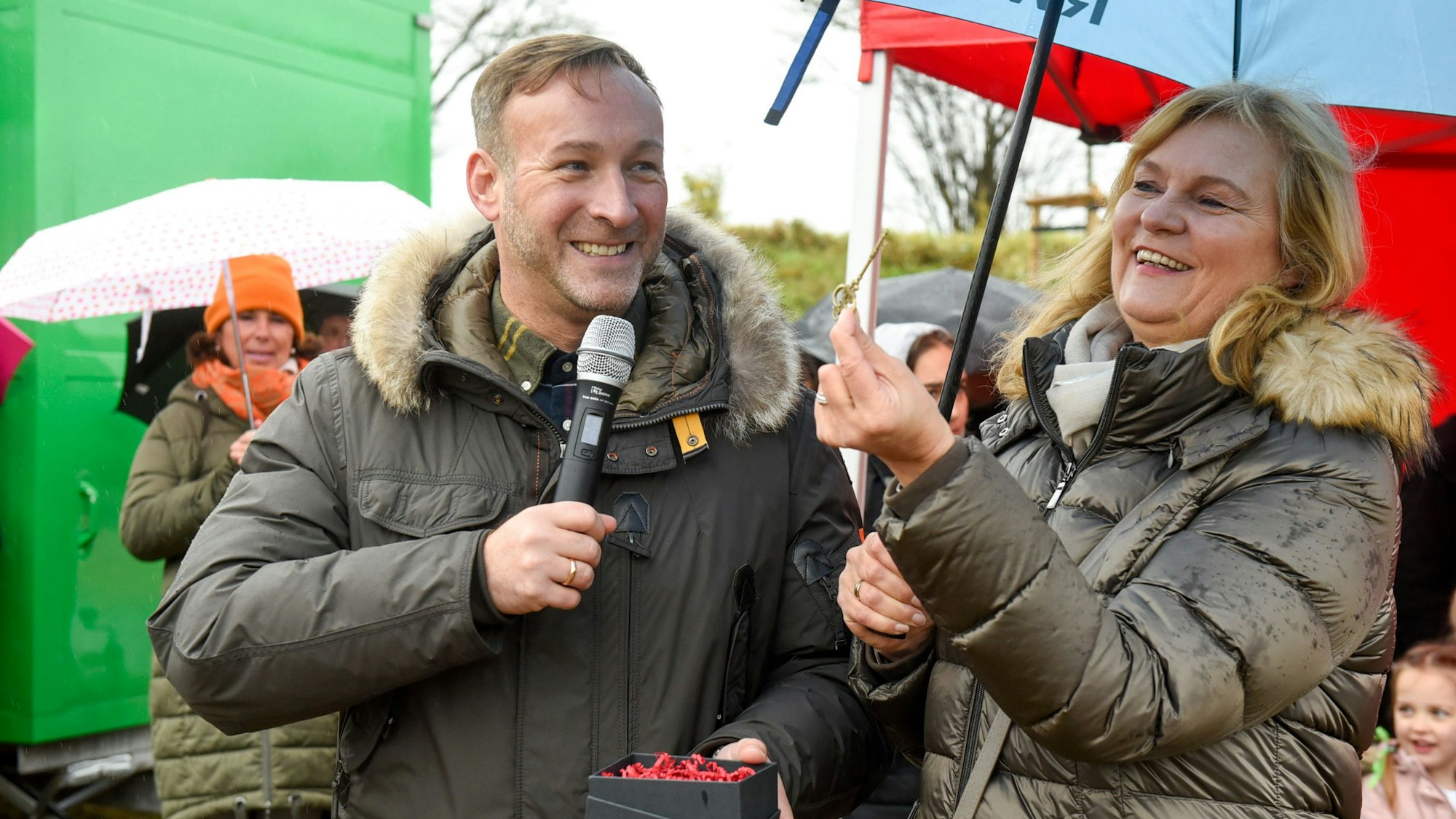 Auf dem Bild ist der Bürgermeister Andreas Heller zu sehen, der einen Schlüssel überreicht.