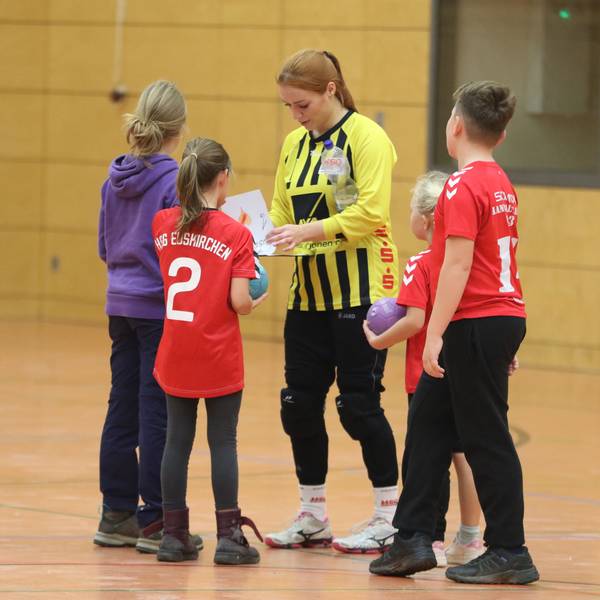 Das Bild zeigt Anna Kurm, die von jungen Fans umringt wird und Autogramme schreibt.