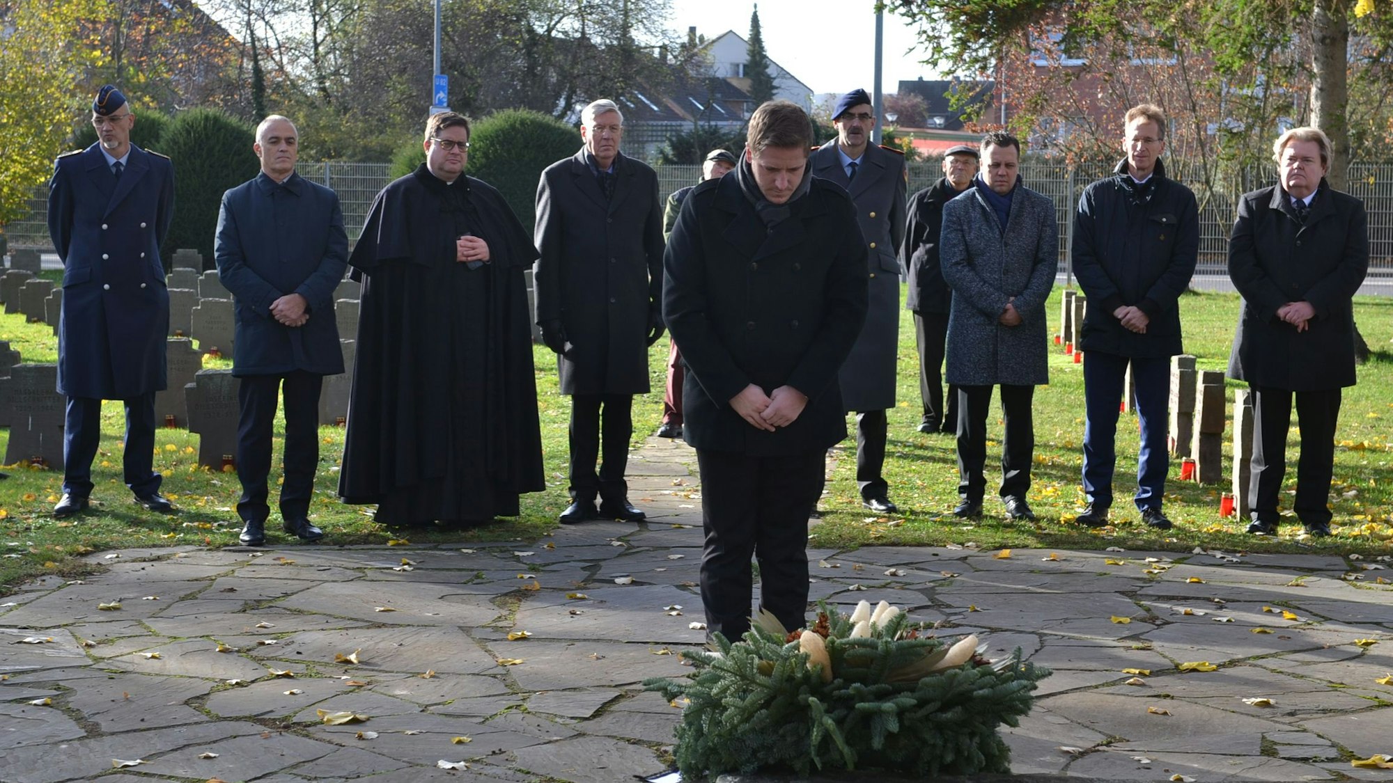 Der Kreis Euskirchener Landrat Markus steht mit gesenktem Kopf vor einem abgelegten Kranz, dahinter eine Reihe mit den Repräsentanten.