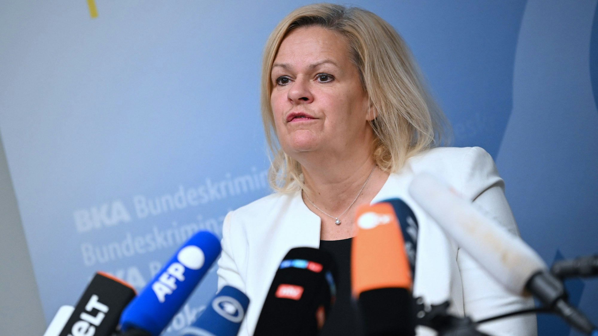 Nancy Faeser steht hinter Mikrofonen und beantwortet Fragen.