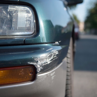 Am Stoßfänger eines geparkten Personenkraftwagens sind Spuren eines Unfalls zu sehen.
