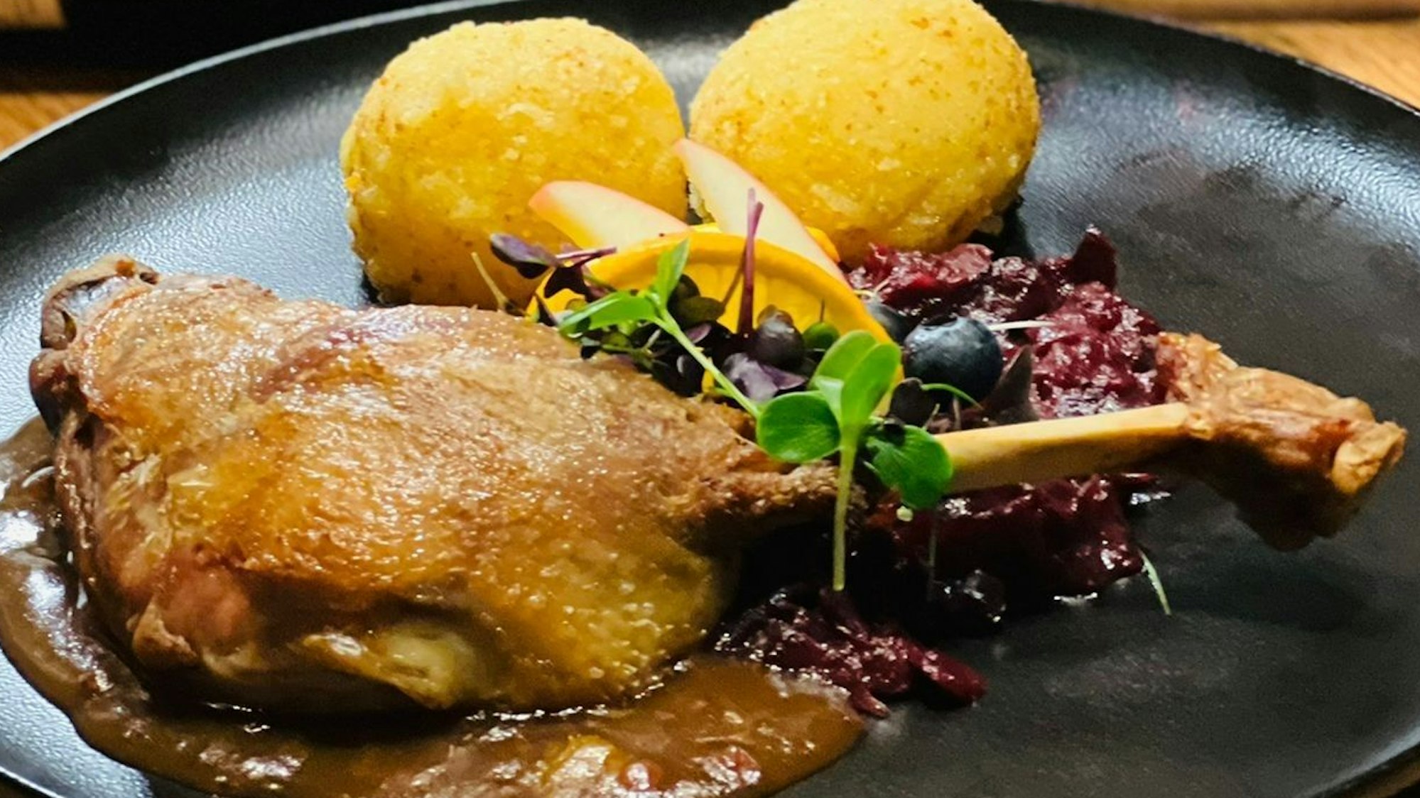 Das Bild zeugt eine Gänsekeule mit Rotkohl und Klößen.
