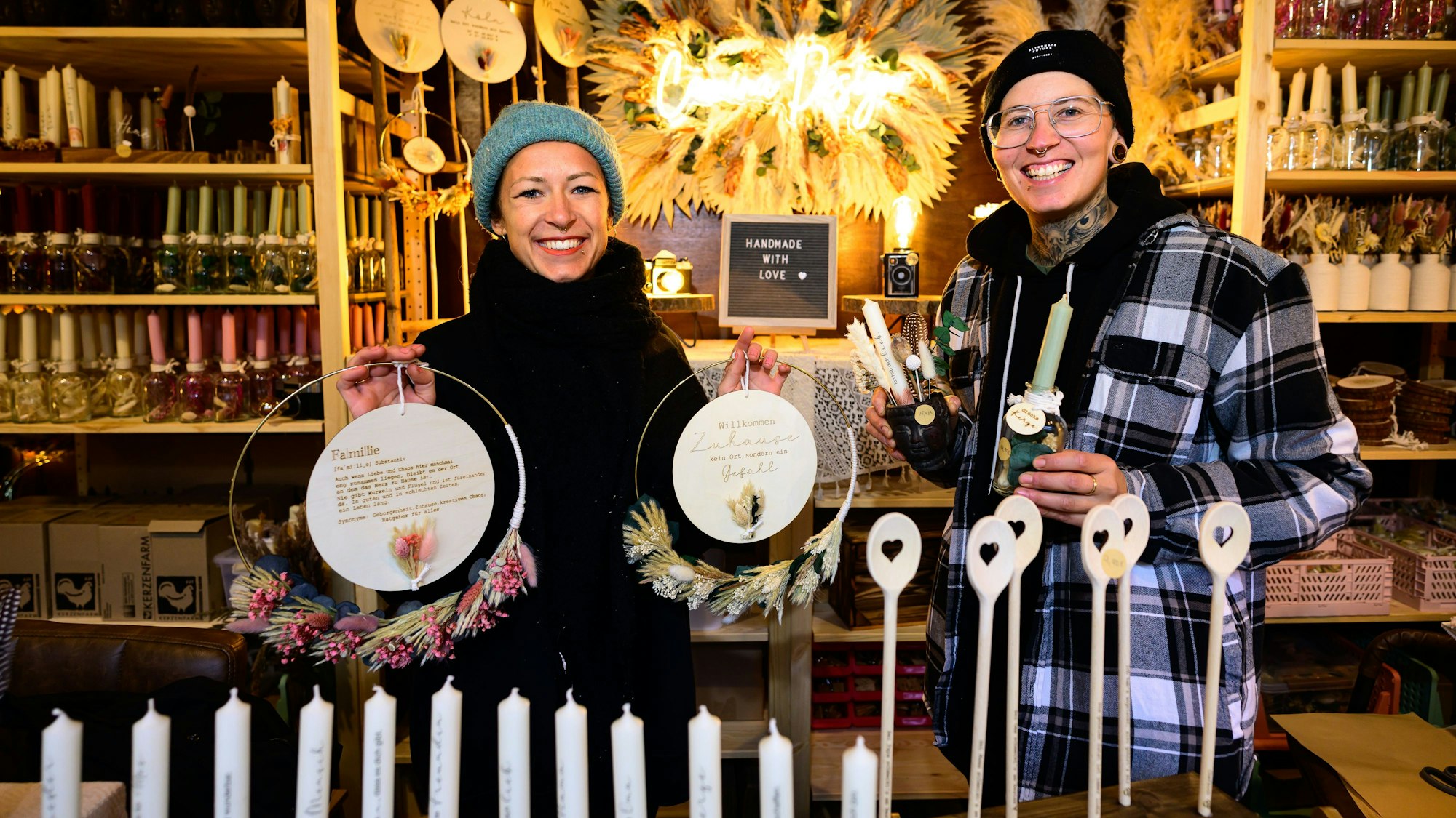 Die beiden jungen Frauen stehen lächelnd in ihrem Stand.