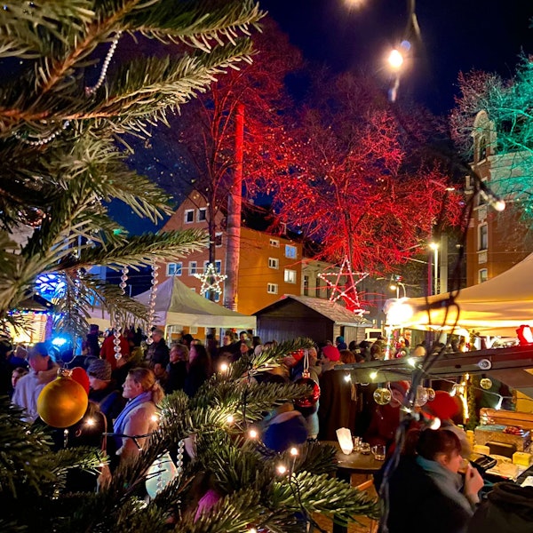 Auf einer Bühne im Freien stehen drei Musiker, vor der Bühne stehen viele Menschen mit Mützen.