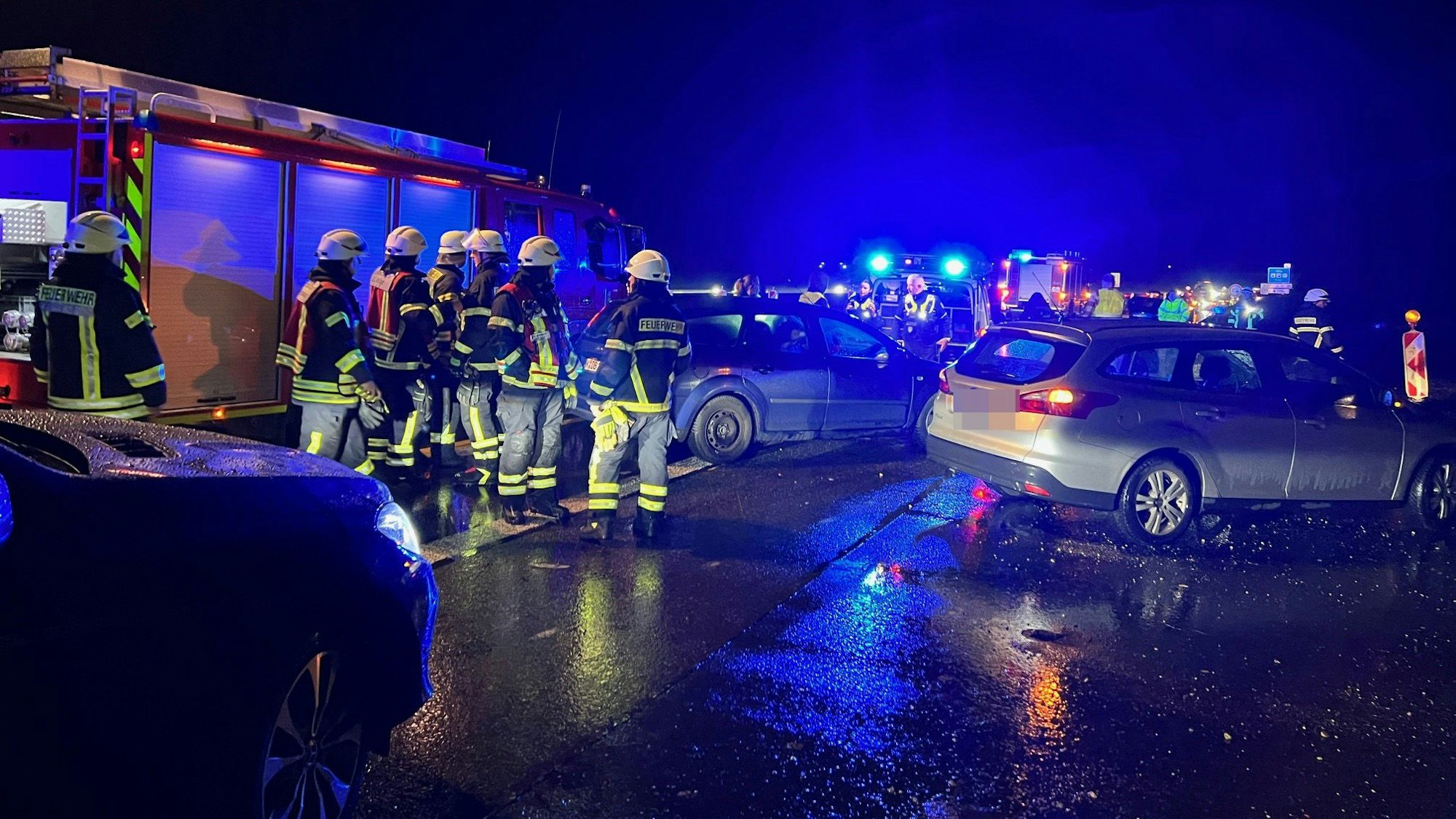 Das Bild zeigt mehrere beschädigte Autos bei Dunkelheit auf der Autobahn.