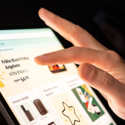 Eine Person tippt mit dem Finger auf ein Tablet, auf dem ein Online-Shop mit Werbung für den Black Friday geöffnet ist.