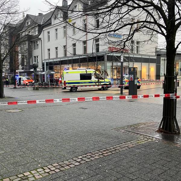 Polizeiautos und Absperrband vor einem Tatort in einer Fußgängerzone.
