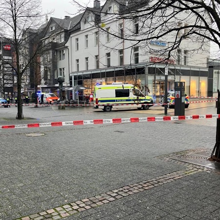 Polizeiautos und Absperrband vor einem Tatort in einer Fußgängerzone.