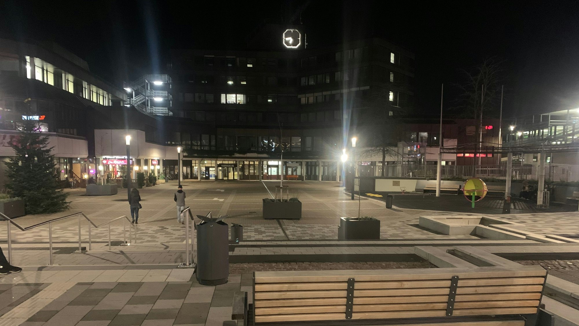 Der Karl-Gatzweiler-Platz am Abend ist öde und leer. Die Uhr am Rathaus in Sankt Augustin zeigt 18.40 Uhr an.