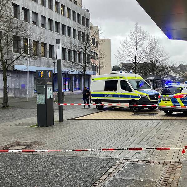 Zwei Polizeiwagen stehen in der Gummersbacher Innenstadt. Um ein Geschäft ist eine Fläche mit Flatterband abgesperrt.
