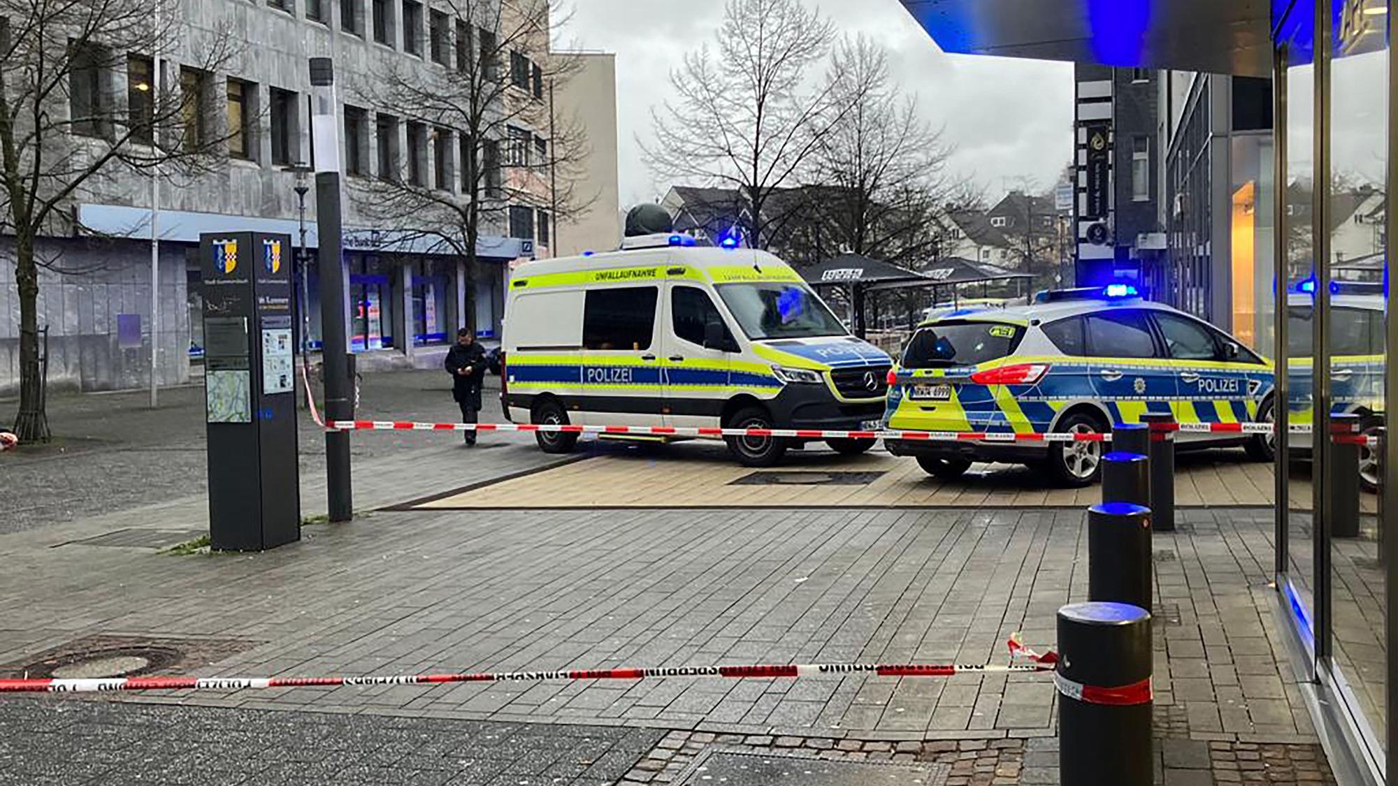 Zwei Polizeiautos stehen an einem Tatort vor einem Backshop. Mit Sperrband ist der Tatort abgesichert.