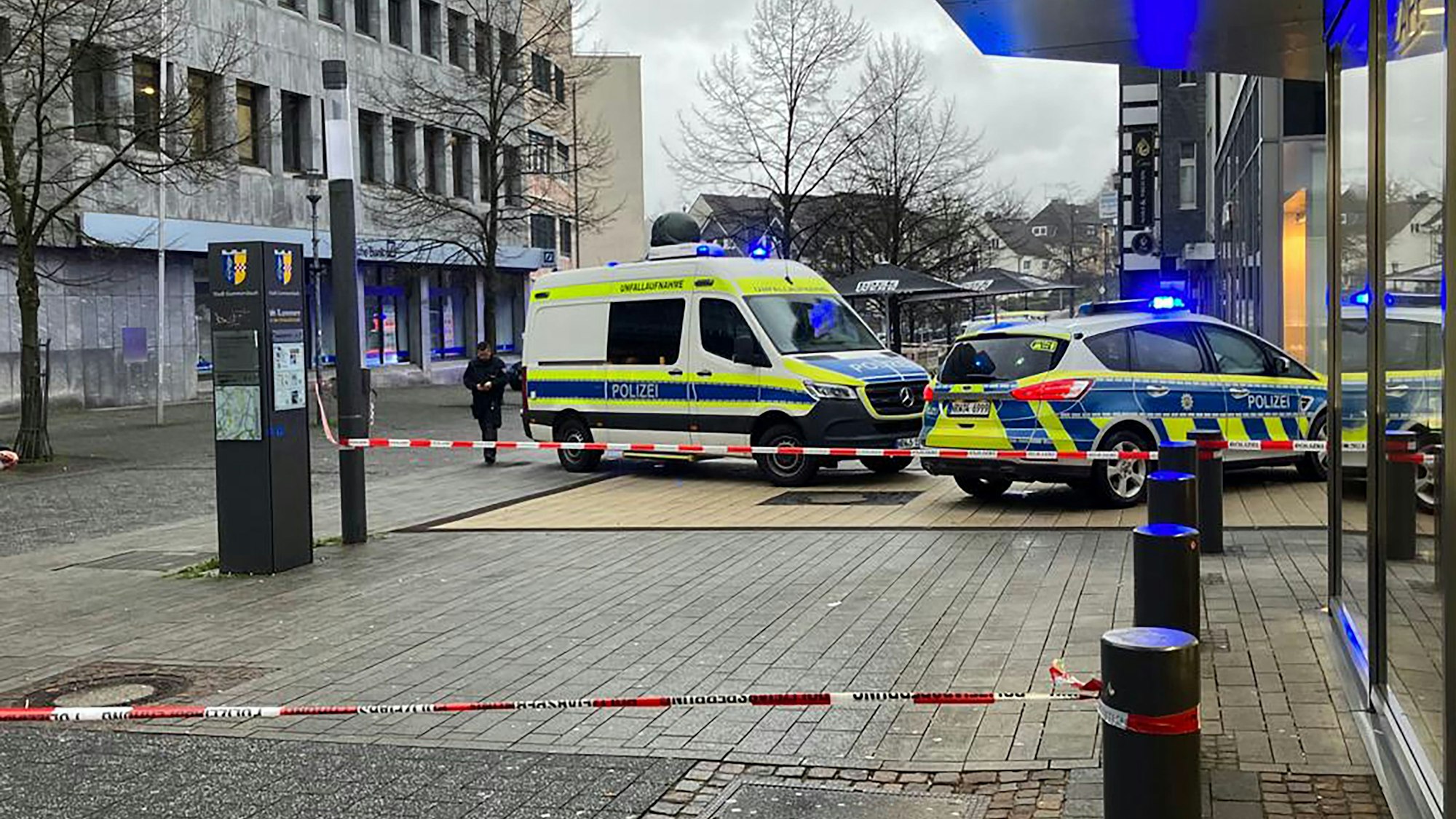 Zwei Polizeiautos stehen an einem Tatort vor einem Backshop. Mit Sperrband ist der Tatort abgesichert.