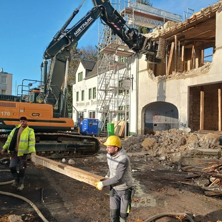 Mit einem Bagger wird ein altes Haus abgerissen
