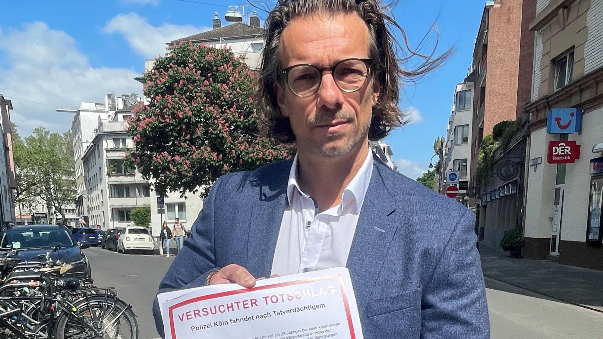Dirk Bachem hält ein Plakat in der Hand auf dem „Versuchter Totschlag“ steht.