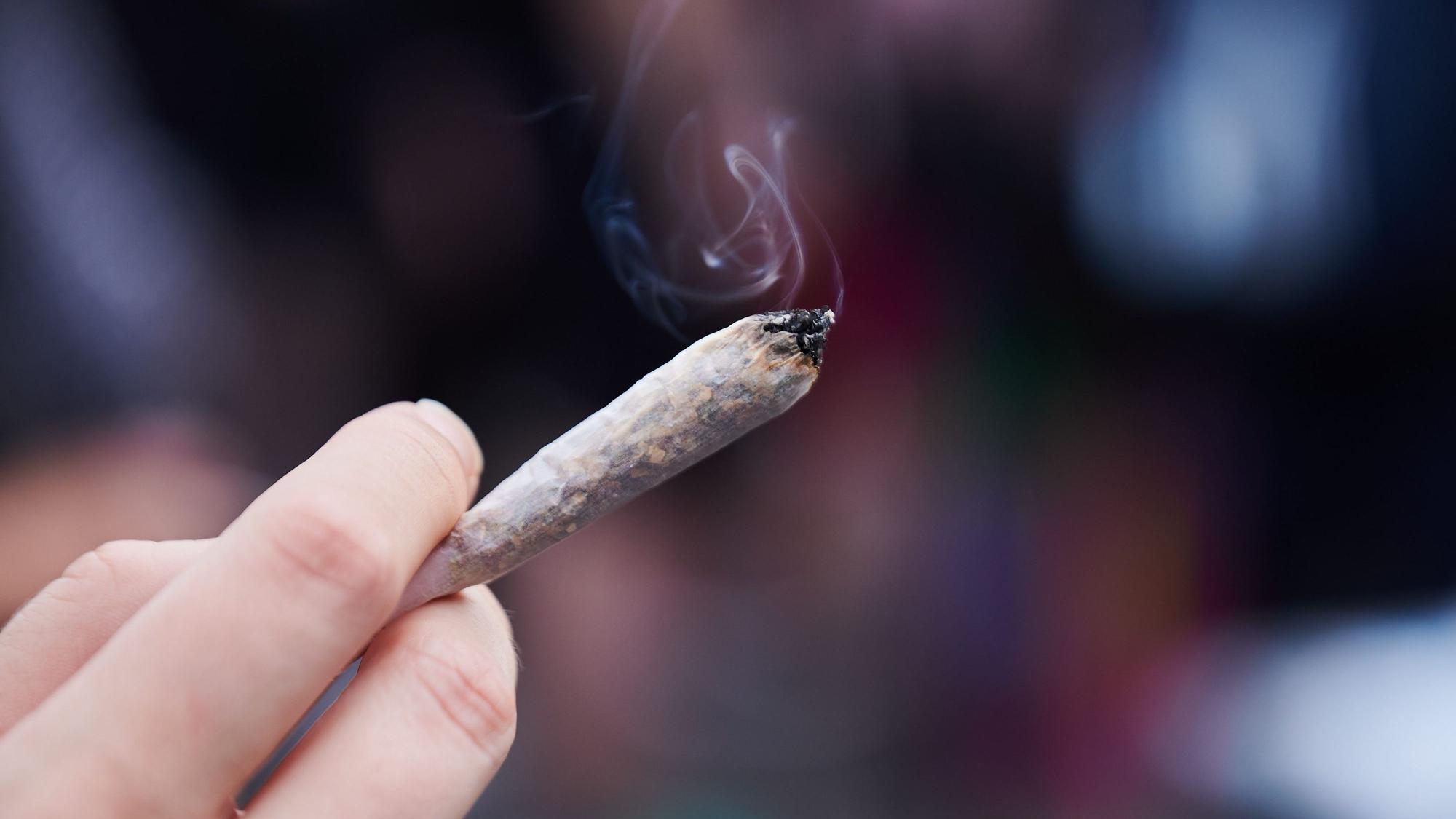 Eine Frau hält einen Joint in der Hand.