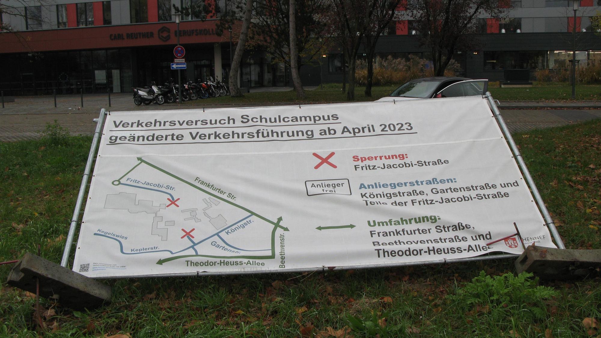 Ein Into-Transparent zum Verkehrsversuch „Autofreier Schulcampus“ ist umgekippt und liegt im Gras.