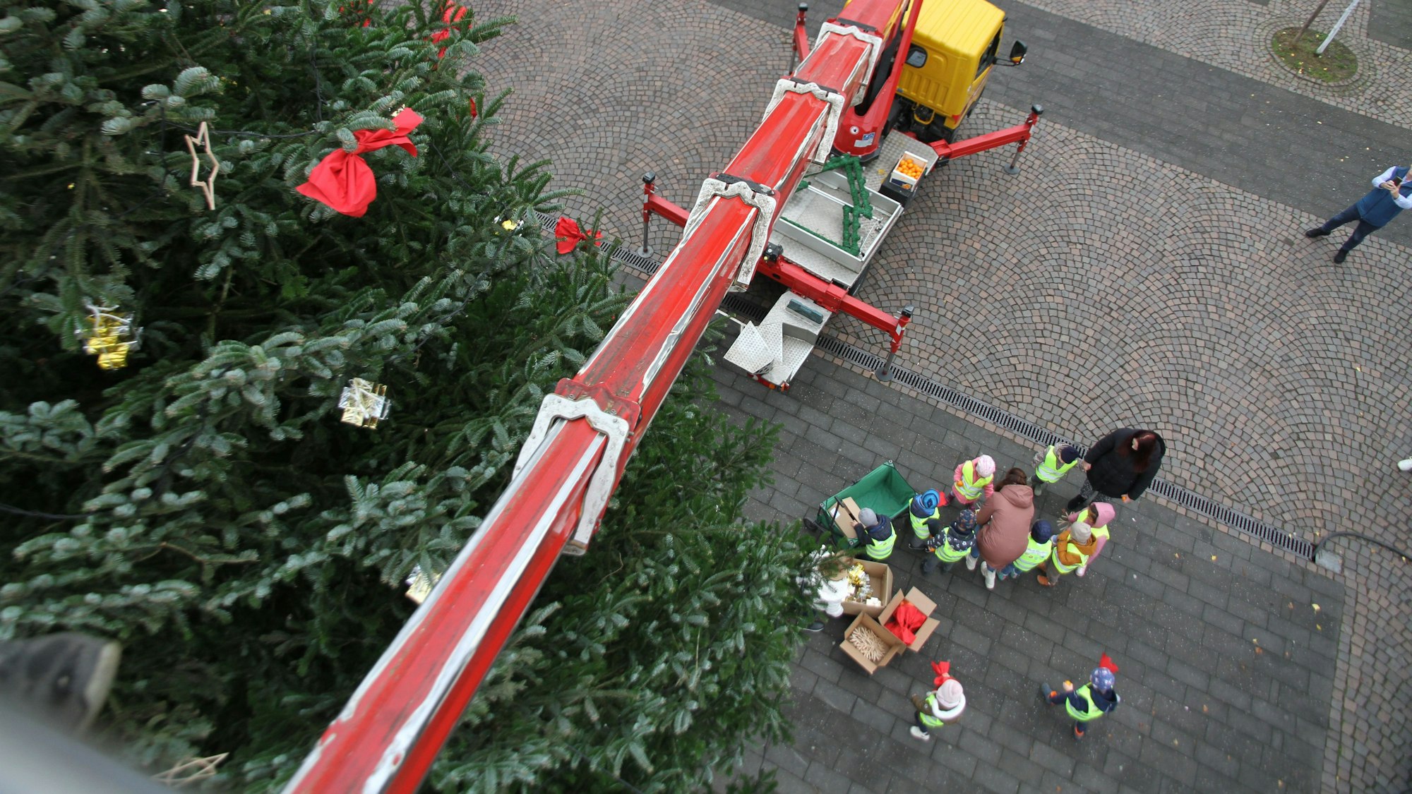 Blick von einer Hubbühne auf einen Weihnachtsbaum, den Markt und eine Gruppe von Kindern