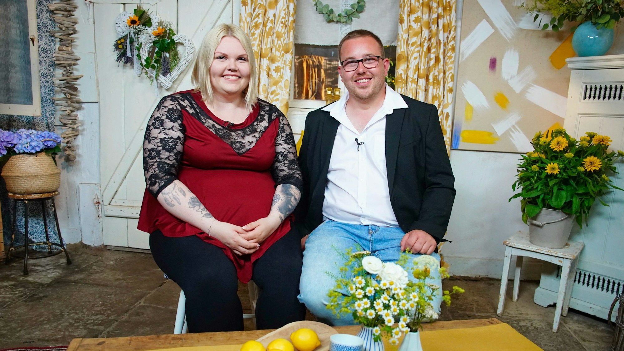 Bauer Stephan und Kandidatin Lisa sitzen nebeneinander und lächeln in die Kamera.