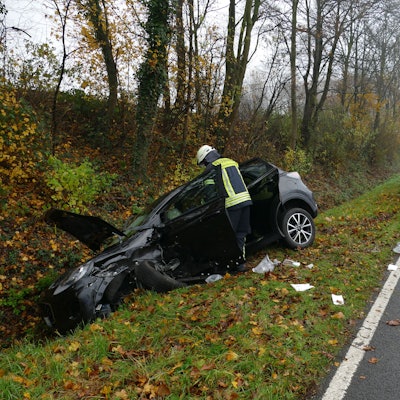 Ein schwarzer PKW liegt nach dem Zusammenstoß bei Pohlhausen auf der B56 mit deutlichen Unfallspuren in einem Graben, die Motorhaube steht offen. Ein Feuerwehrmann beugt sich über das Fahrzeug.