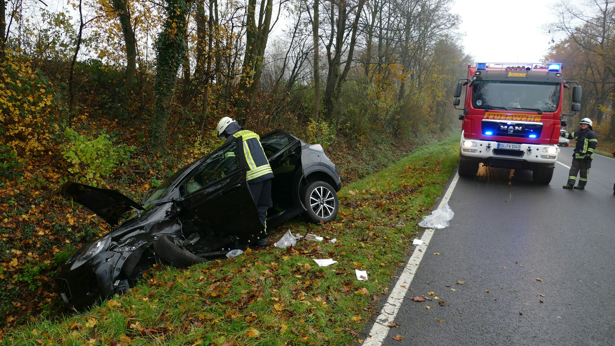 Ein schwarzer PKW liegt nach dem Zusammenstoß bei Pohlhausen auf der B56 mit deutlichen Unfallspuren in einem Graben, die Motorhaube steht offen. Ein Feuerwehrmann beugt sich über das Fahrzeug.
