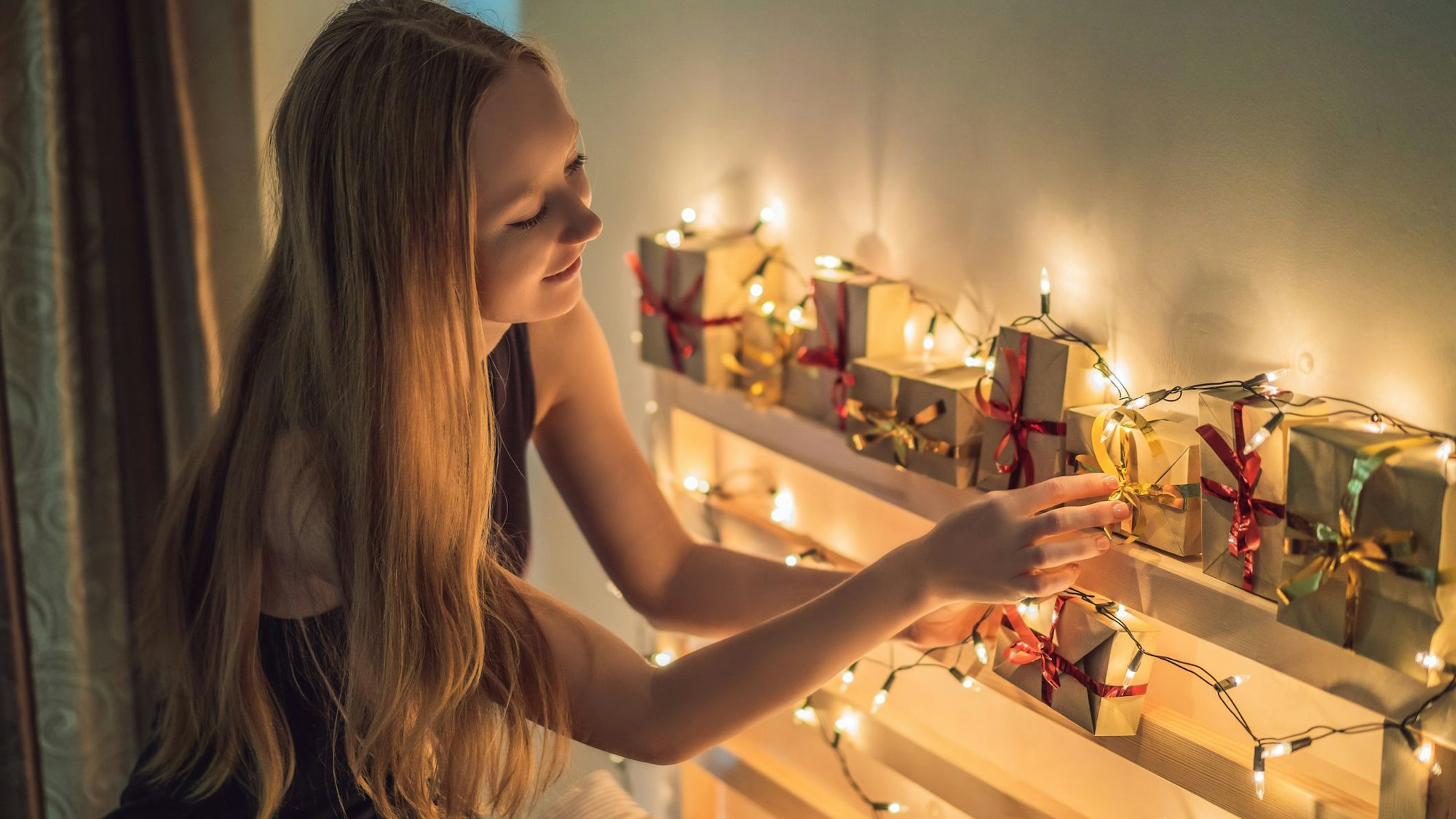 Ein jugendliches Mädchen betrachtet glücklich einen Adventskalender.