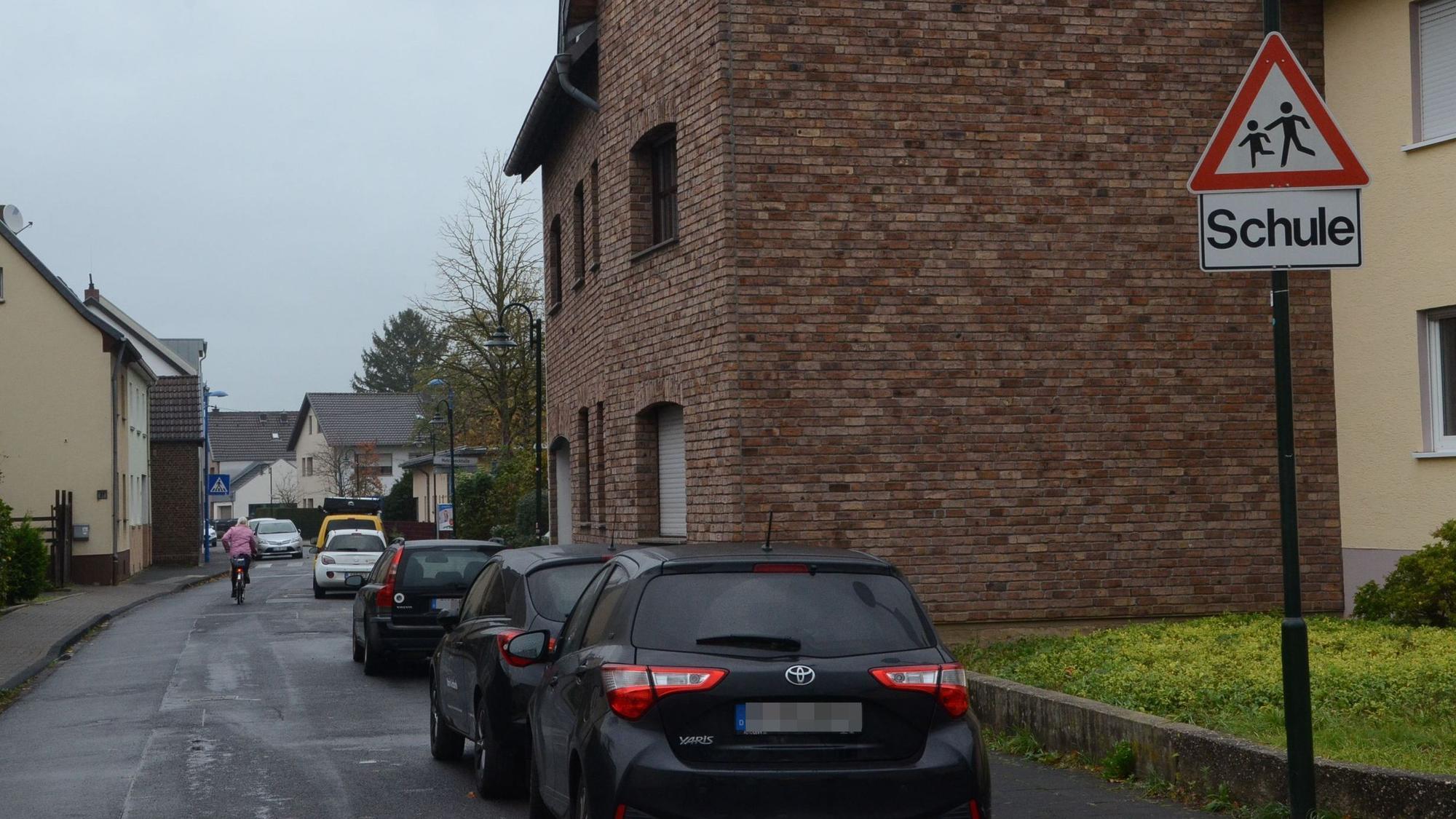 Geparkte Autos an einer Straße in Müllekoven. Ein Warnschild weist auf die nahe Schule hin.