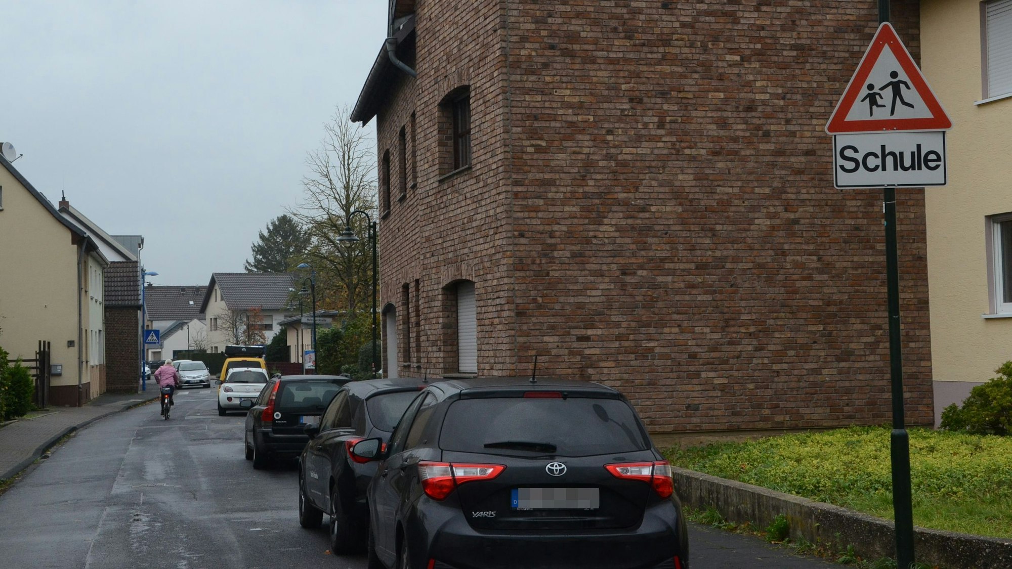 Geparkte Autos an einer Straße in Müllekoven. Ein Warnschild weist auf die nahe Schule hin.
