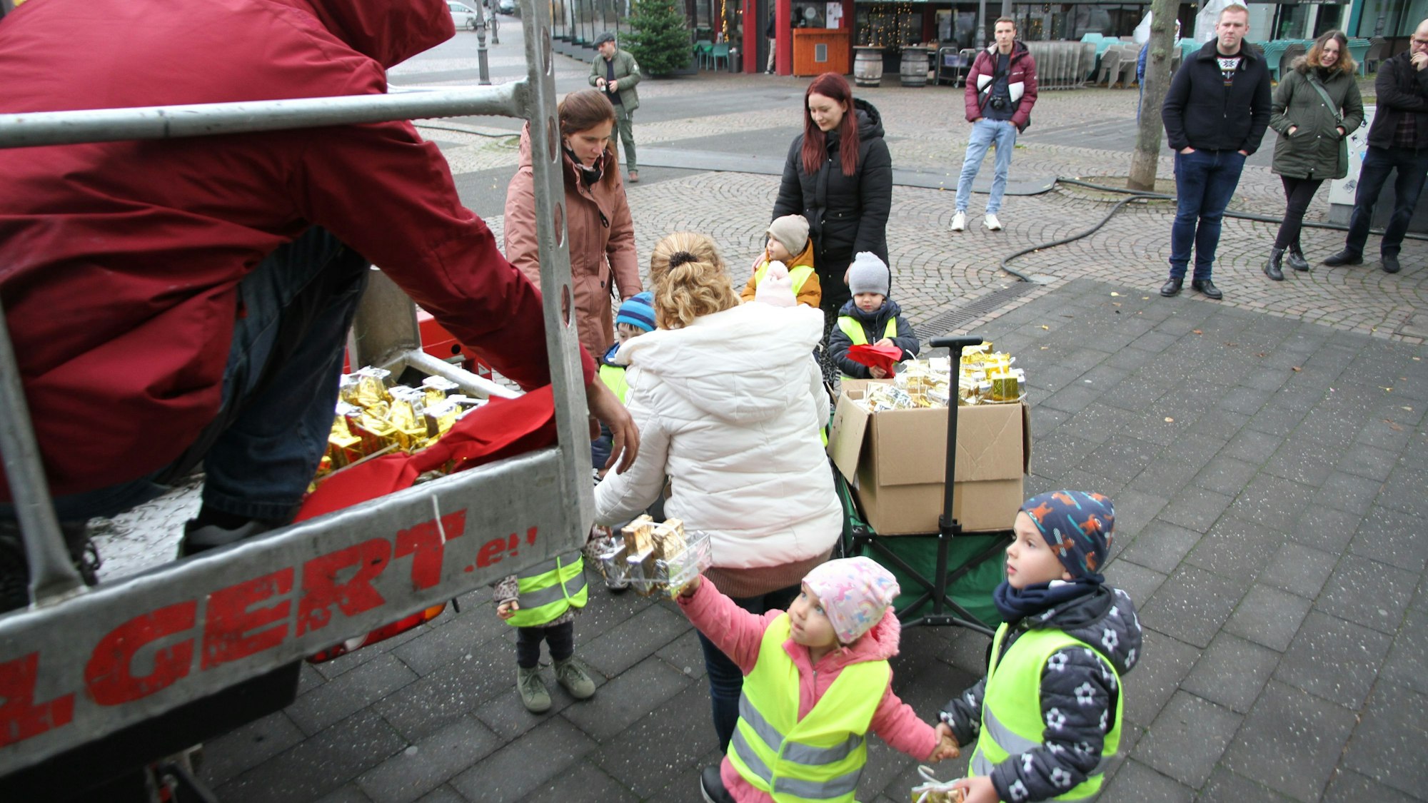 Ein Mädchen reicht dem Mitarbeiter einer Fachfirma auf einem Hubwagen ein Dekopaket an