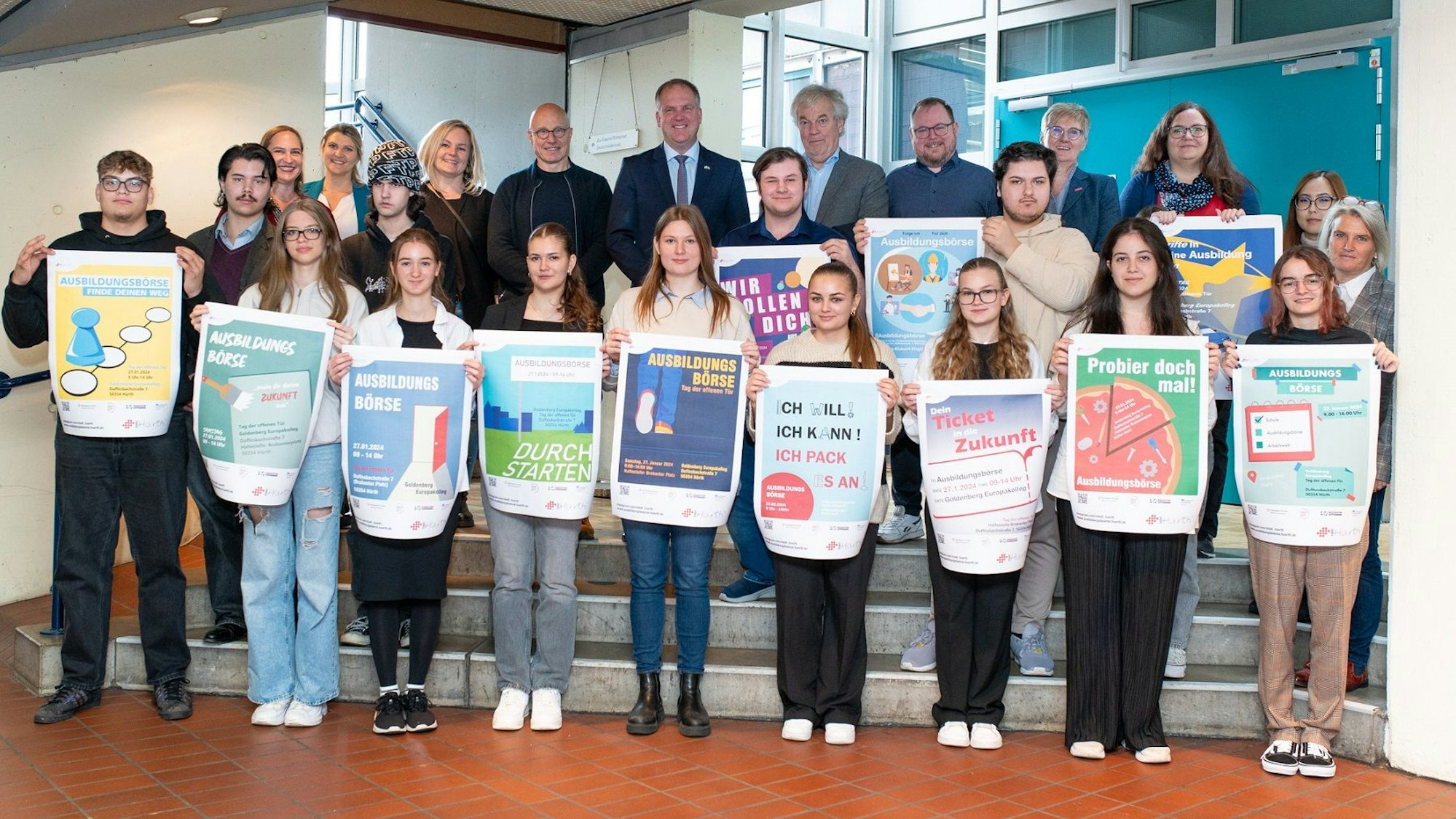 Eine Gruppe von Schülerinnen und Schülern mit Plakaten in den Händen sowie die Mitglieder der Jury.