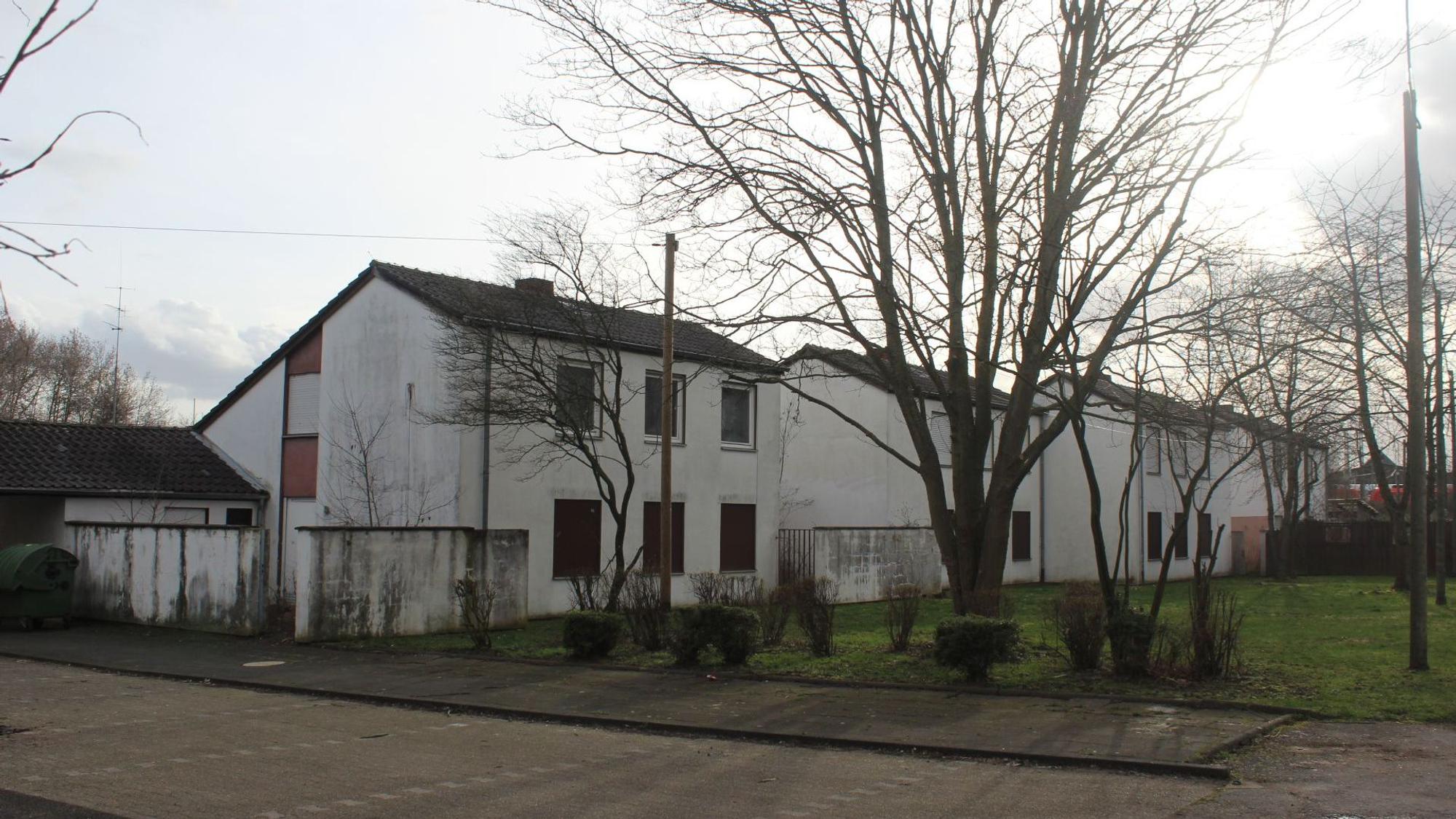 Mehrere zweigeschossige Häuser stehen an einer Wiese.