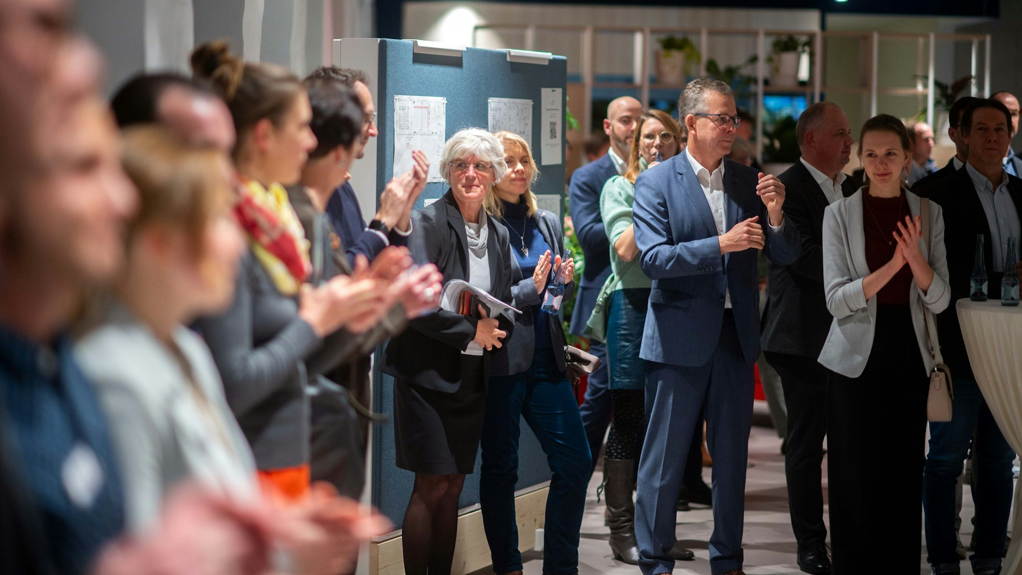 Das Bild zeigt Gäste, die während einer Rede Applaus spenden.