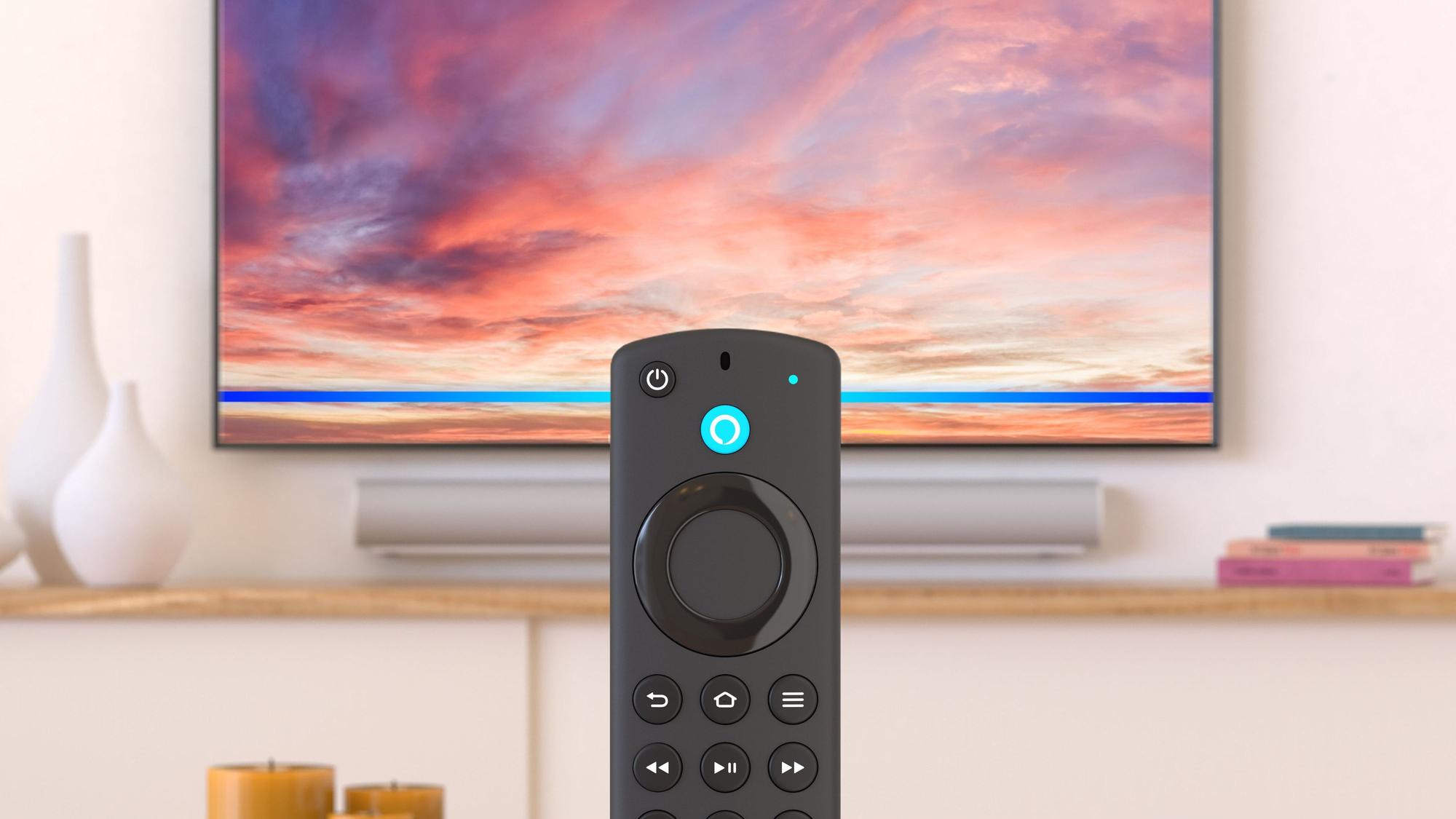 Die Fernbedienung eines Fire TV Sticks ist vor dem Ausschnitt eines Wohnzimmers mit Fernseher an der Wand zu sehen.