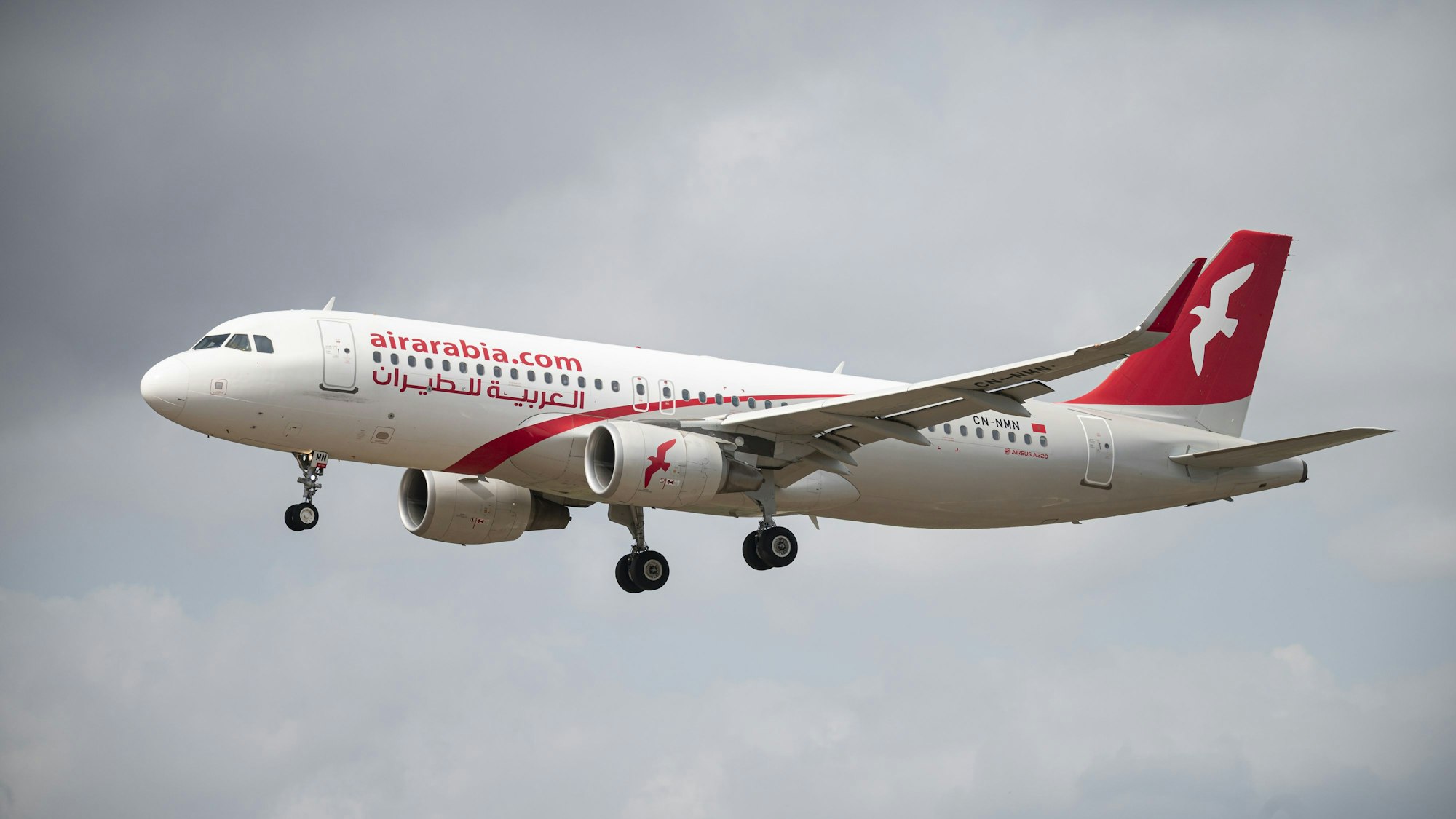 Ein Airbus A320 der arabischen Fluggesellschaft Air Arabia im Landenanflug während eines Unwetters. Das Flugzeug ist markant in rot und weiß lackiert. (Symbolbild)