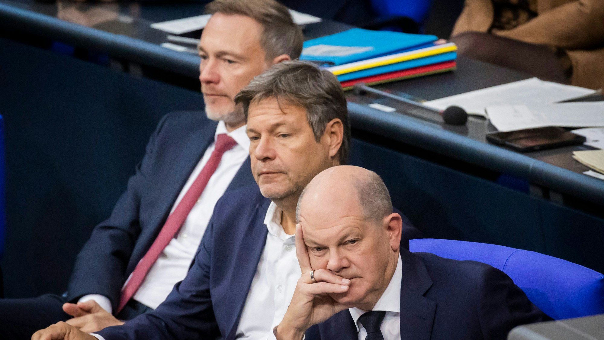 Bundeskanzler Olaf Scholz (SPD, r-l), Robert Habeck (Bündnis 90/Die Grünen), Bundesminister für Wirtschaft und Klimaschutz, und Christian Lindner (FDP), Bundesminister der Finanzen, sitzen im Plenum des Deutschen Bundestages und verfolgen die Debatte. (Symbolbild)