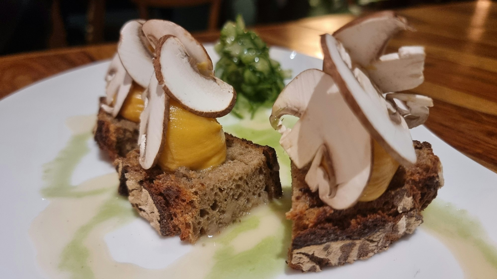 Zwei Brotscheiben, darauf Käsecreme und Champignons.
