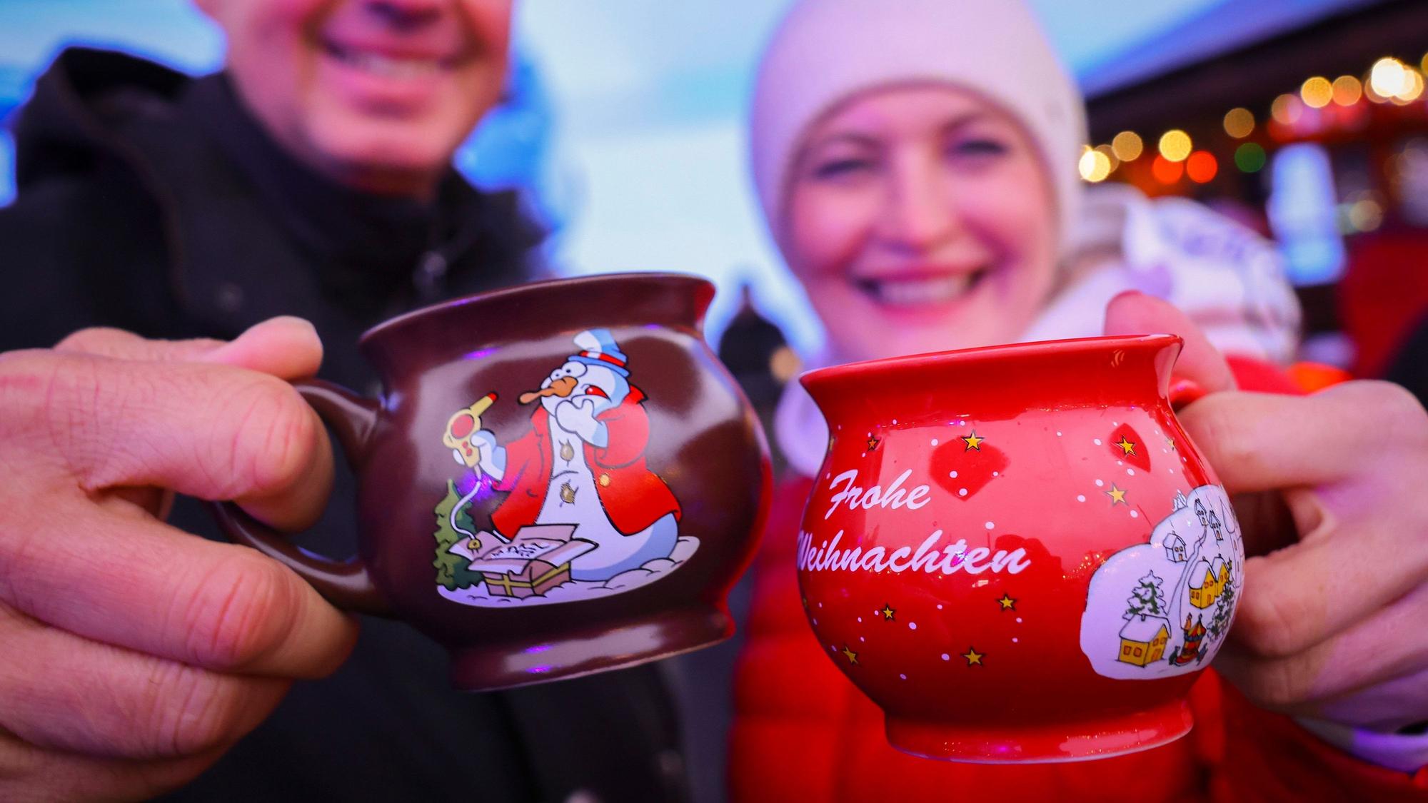 13.11.2023, Hamburg: Ein Paar hält zwei Tassen mit heißem Glühwein kurz nach der Eröffnung des "Santa Pauli" Weihnachtsmarkt· auf dem Spielbudenplatz. Am Montag wurde der sündige Weihnachtsmarkt ·Santa Pauli· auf der Reeperbahn eröffnet. Foto: Christian Charisius/dpa +++ dpa-Bildfunk +++