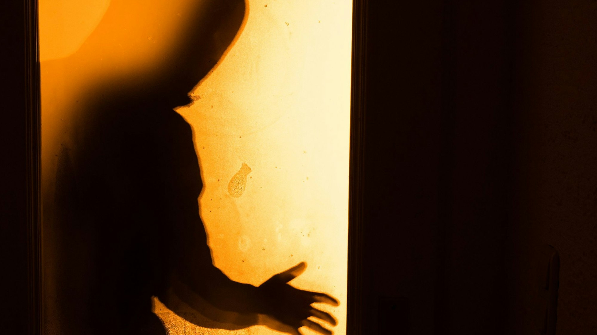 Das Bild zeigt eine Person, die im Schatten eines Lichtkegels steht.